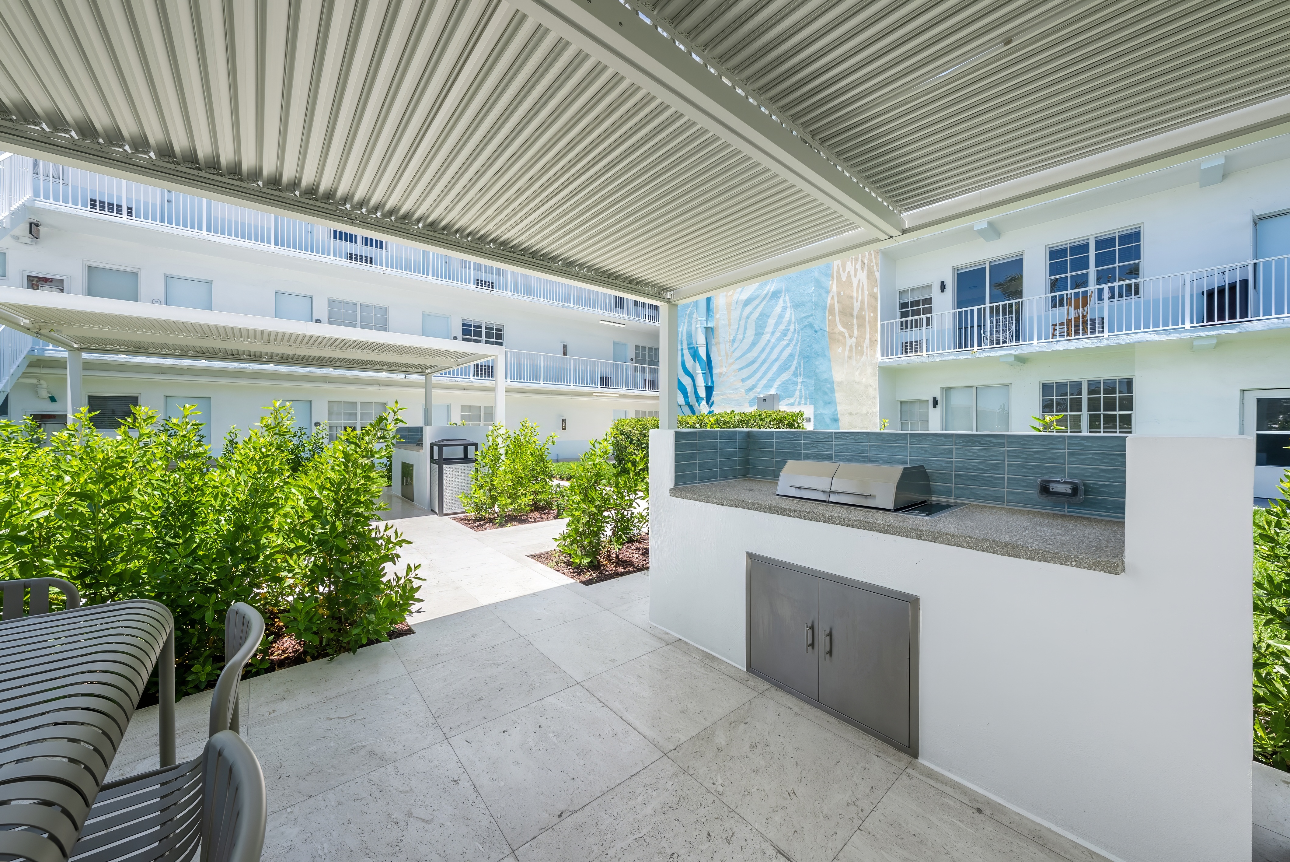 A patio with a bench and a table with a grill on it.